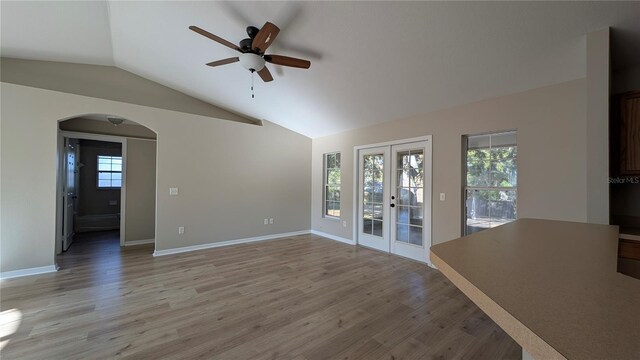 unfurnished living room with lofted ceiling, a wealth of natural light, light hardwood / wood-style floors, and french doors