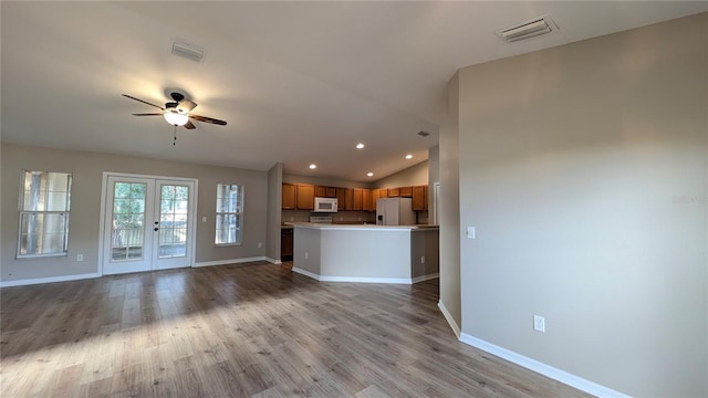 unfurnished living room with lofted ceiling, light hardwood / wood-style flooring, french doors, and ceiling fan