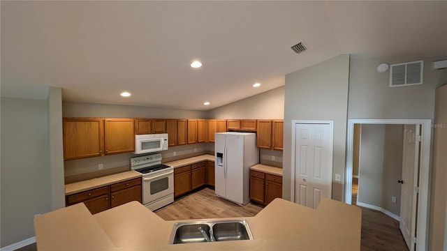 kitchen with lofted ceiling, light wood-type flooring, sink, and white appliances