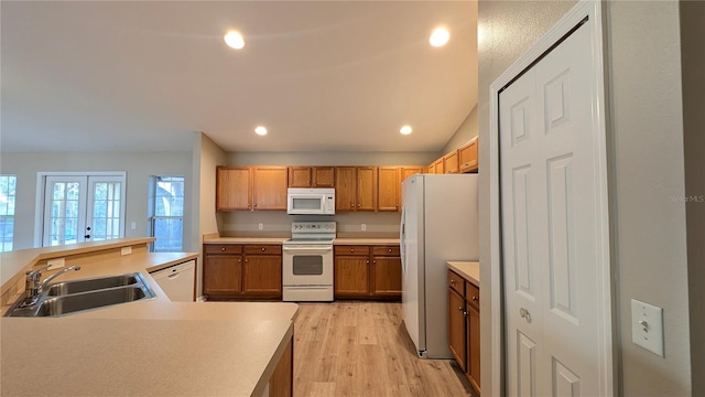 kitchen featuring french doors, sink, light wood-type flooring, kitchen peninsula, and white appliances