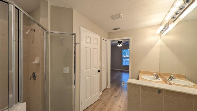 bathroom with wood-type flooring, an enclosed shower, sink, and a textured ceiling