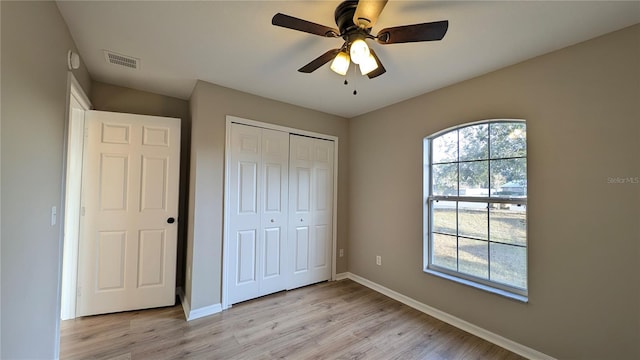 unfurnished bedroom with light hardwood / wood-style flooring, a closet, and ceiling fan