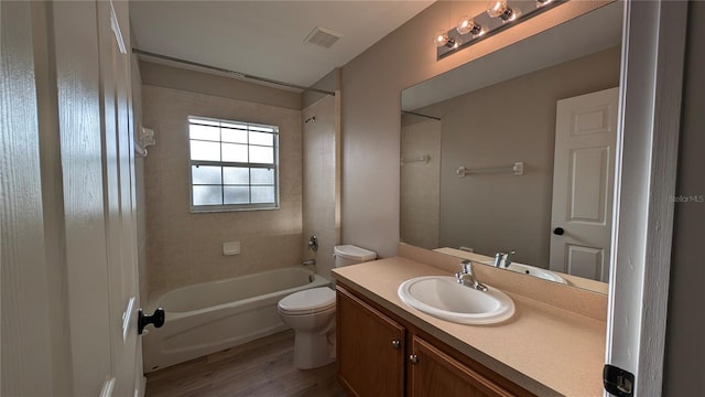 full bathroom featuring vanity, tiled shower / bath combo, wood-type flooring, and toilet