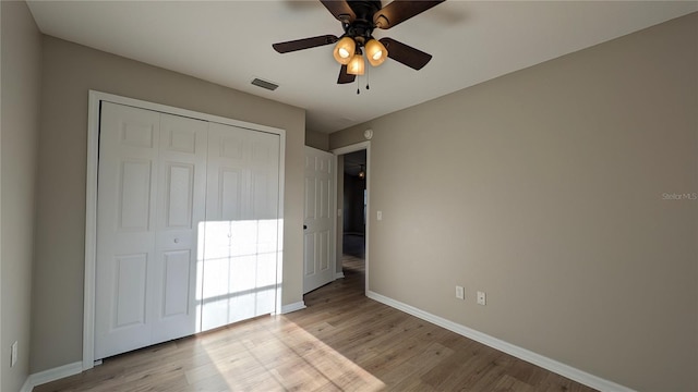 unfurnished bedroom featuring ceiling fan, a closet, and light wood-type flooring