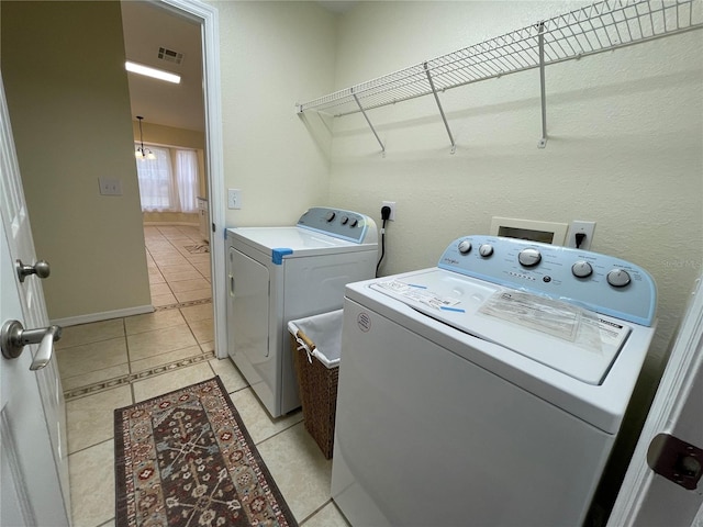 laundry area with independent washer and dryer and light tile patterned floors