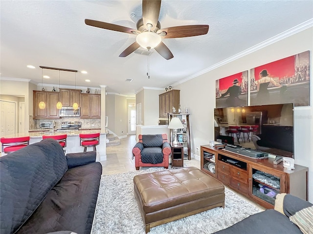 living room featuring ceiling fan, ornamental molding, and sink