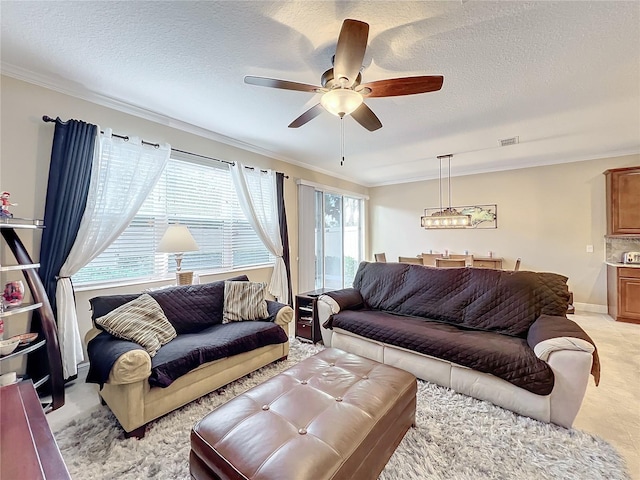 living room with ceiling fan, a textured ceiling, and ornamental molding