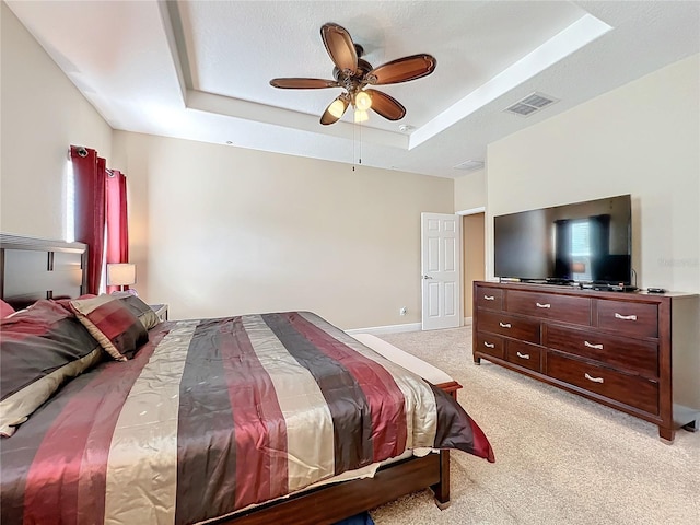 carpeted bedroom featuring ceiling fan and a tray ceiling