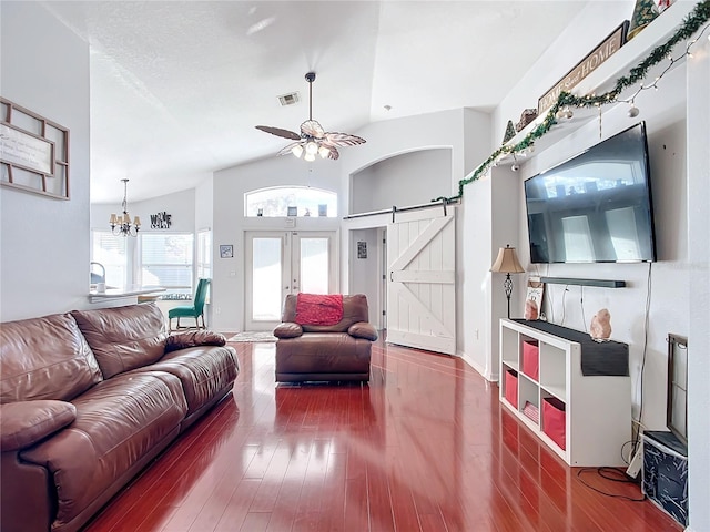 living room with french doors, a barn door, wood-type flooring, vaulted ceiling, and ceiling fan with notable chandelier