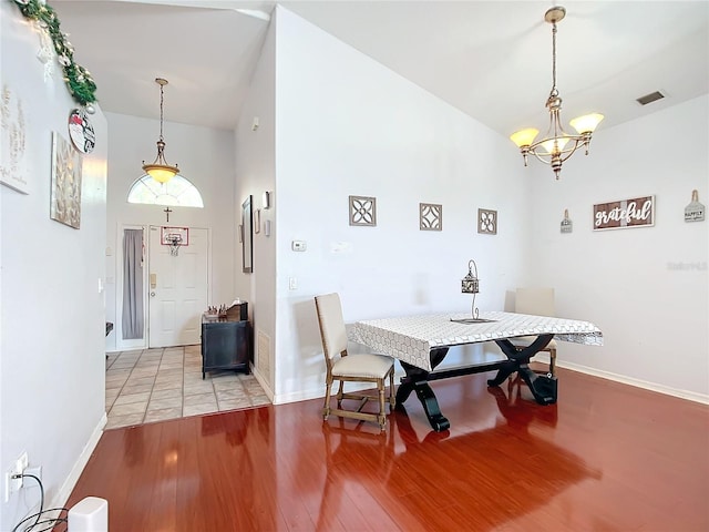 dining space featuring a high ceiling, a notable chandelier, and light wood-type flooring