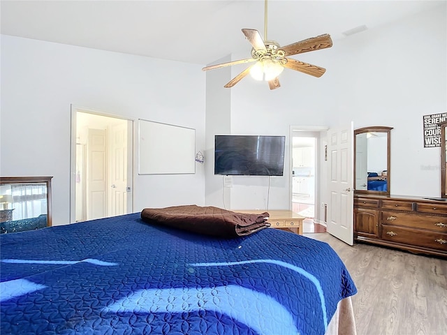 bedroom with ceiling fan, light hardwood / wood-style floors, lofted ceiling, and connected bathroom