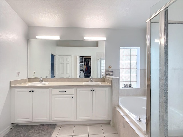 bathroom with tile patterned flooring, vanity, a textured ceiling, and plus walk in shower