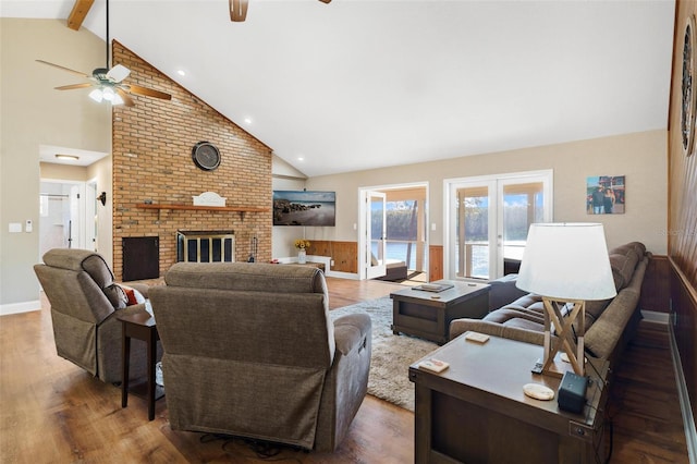 living room featuring beam ceiling, ceiling fan, a fireplace, and hardwood / wood-style floors