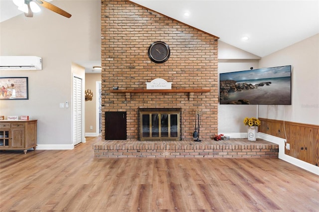 unfurnished living room with vaulted ceiling, a wall unit AC, wooden walls, a fireplace, and light hardwood / wood-style floors