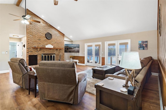 living room featuring beamed ceiling, french doors, dark hardwood / wood-style flooring, and a brick fireplace