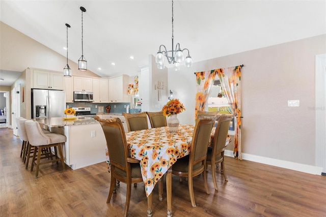 dining space featuring vaulted ceiling, dark wood-type flooring, and a notable chandelier