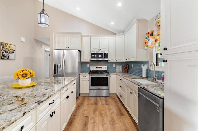 kitchen with sink, backsplash, decorative light fixtures, white cabinets, and appliances with stainless steel finishes