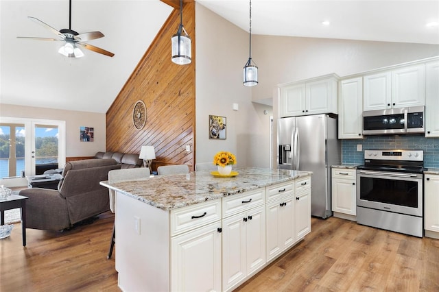 kitchen featuring pendant lighting, appliances with stainless steel finishes, a kitchen island, white cabinetry, and a breakfast bar area