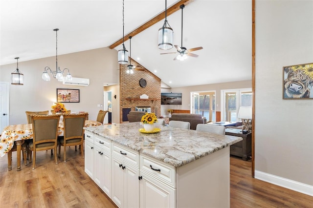 kitchen with white cabinets, decorative light fixtures, a brick fireplace, and a wall unit AC