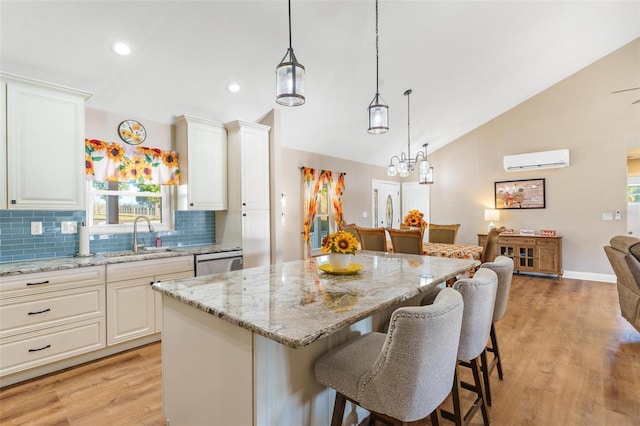 kitchen with backsplash, a wall mounted AC, sink, a center island, and white cabinetry