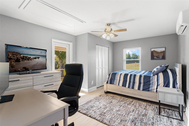 bedroom featuring an AC wall unit, multiple windows, ceiling fan, and light hardwood / wood-style flooring