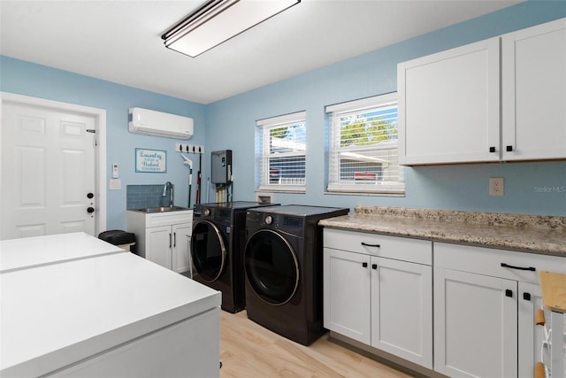 washroom featuring a wall mounted air conditioner, cabinets, sink, independent washer and dryer, and light hardwood / wood-style floors