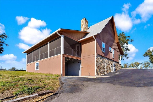 view of side of home with central AC, a garage, and a sunroom