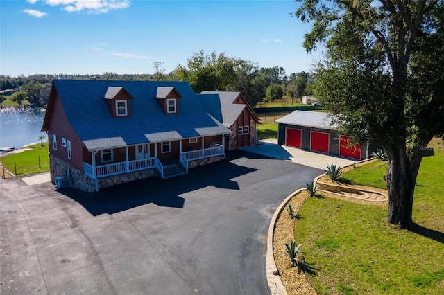 view of front of home featuring a garage, an outbuilding, a water view, and a front lawn