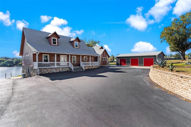 view of front facade featuring an outbuilding, a water view, covered porch, and a garage