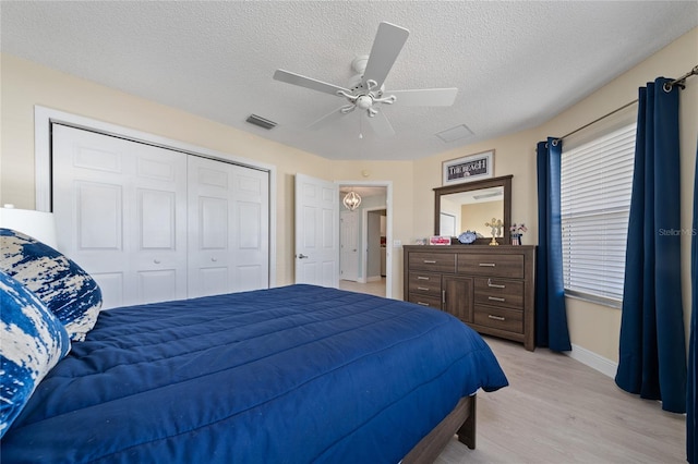 bedroom with a textured ceiling, ceiling fan, a closet, and light hardwood / wood-style flooring