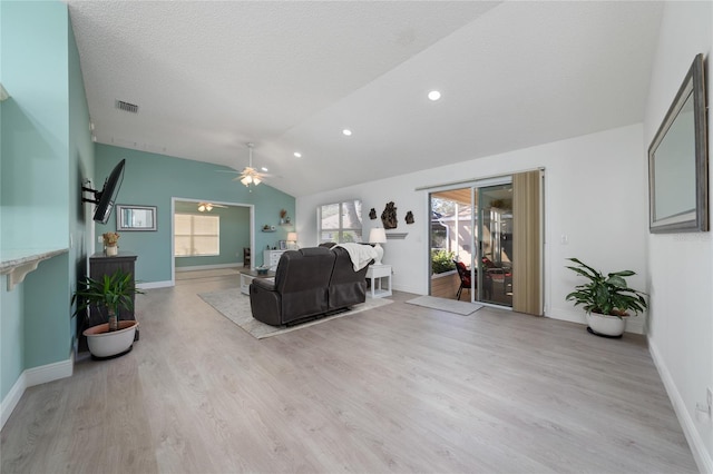 living room featuring ceiling fan, a textured ceiling, light hardwood / wood-style flooring, and lofted ceiling