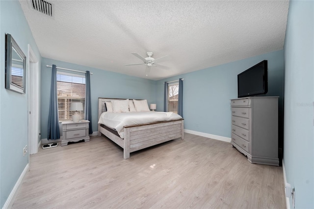 bedroom with a textured ceiling, ceiling fan, and light hardwood / wood-style flooring