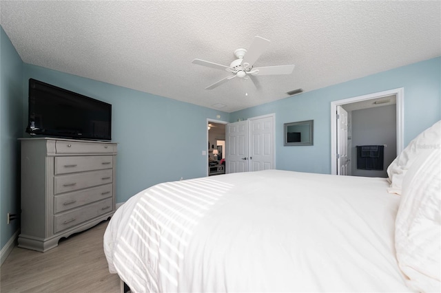 bedroom featuring ceiling fan, light wood-type flooring, and a textured ceiling