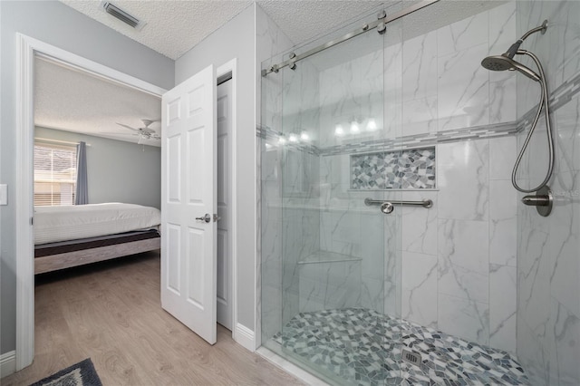 bathroom with hardwood / wood-style flooring, a textured ceiling, an enclosed shower, and ceiling fan