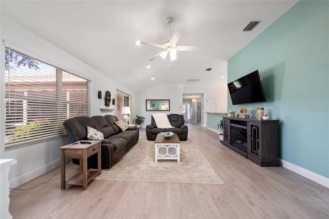 living room featuring ceiling fan, a textured ceiling, vaulted ceiling, and light wood-type flooring