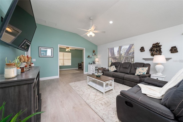 living room with ceiling fan, light hardwood / wood-style floors, a textured ceiling, and lofted ceiling