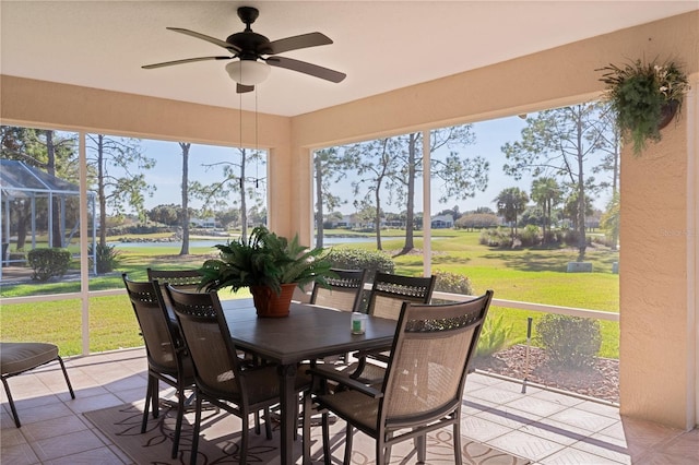 sunroom featuring ceiling fan and a water view