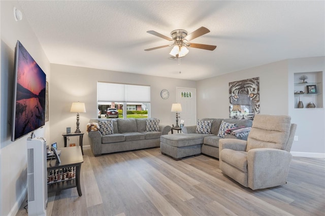 living room featuring ceiling fan, light hardwood / wood-style floors, and a textured ceiling