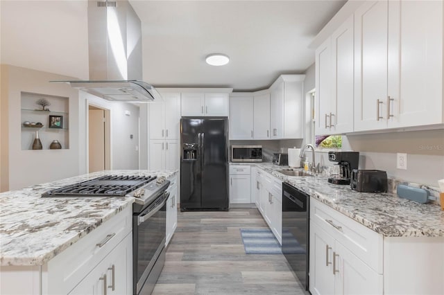 kitchen with light stone counters, island range hood, sink, black appliances, and white cabinets