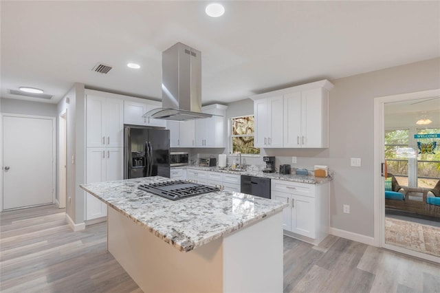 kitchen featuring island exhaust hood, stainless steel appliances, a center island, white cabinetry, and plenty of natural light