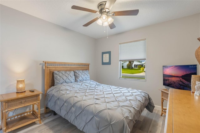 bedroom with hardwood / wood-style flooring, ceiling fan, and a textured ceiling