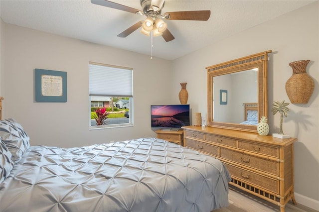 bedroom with ceiling fan, a textured ceiling, and hardwood / wood-style flooring