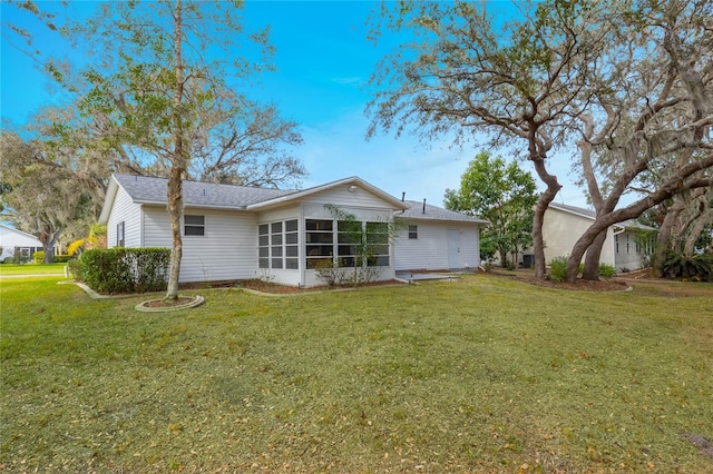 rear view of house featuring a sunroom and a yard