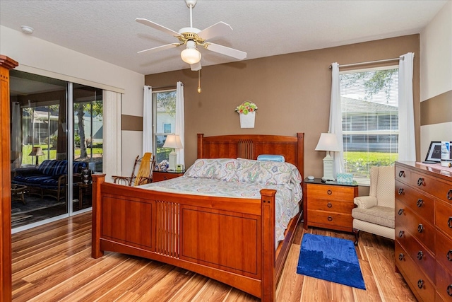 bedroom featuring a textured ceiling, light wood-type flooring, access to outside, and ceiling fan