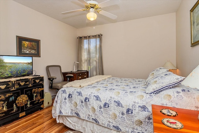 bedroom with hardwood / wood-style floors, ceiling fan, and a textured ceiling