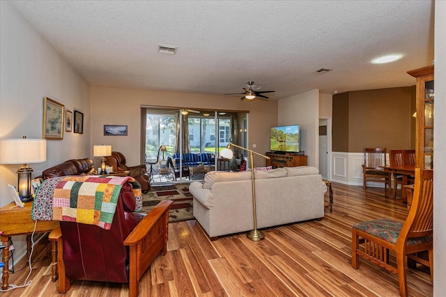 living room with ceiling fan, a textured ceiling, and hardwood / wood-style flooring