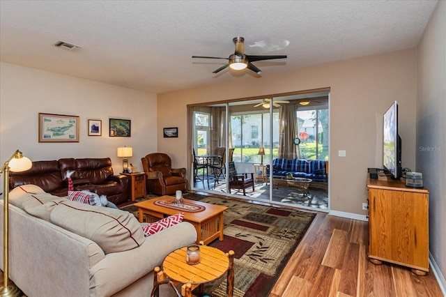 living room featuring ceiling fan, a textured ceiling, and hardwood / wood-style flooring