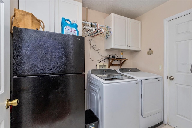 laundry area with washing machine and clothes dryer, cabinets, and a textured ceiling