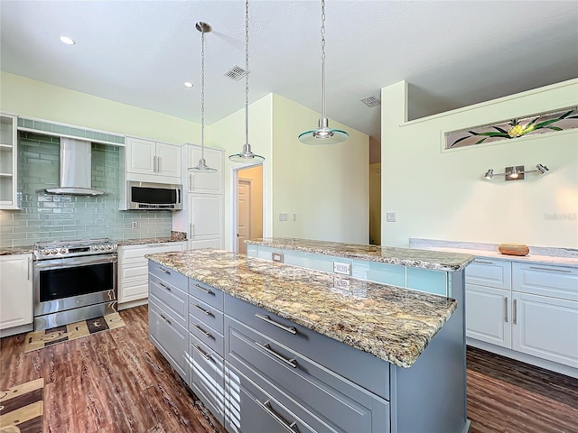 kitchen with a center island, white cabinets, stainless steel appliances, and wall chimney range hood