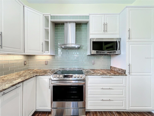 kitchen featuring white cabinetry, wall chimney exhaust hood, stainless steel appliances, dark stone counters, and decorative backsplash